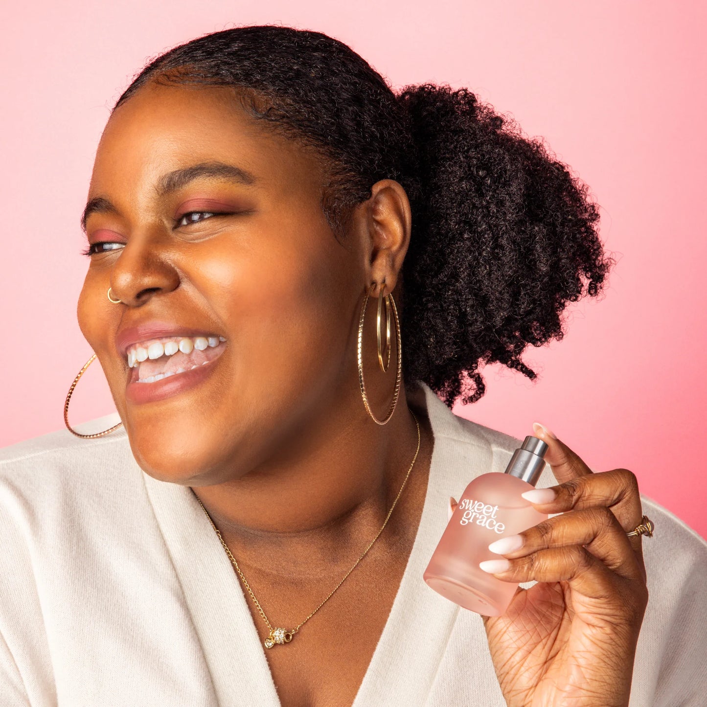 smiling person holding a bottle of Sweet Grace Eau de Parfum