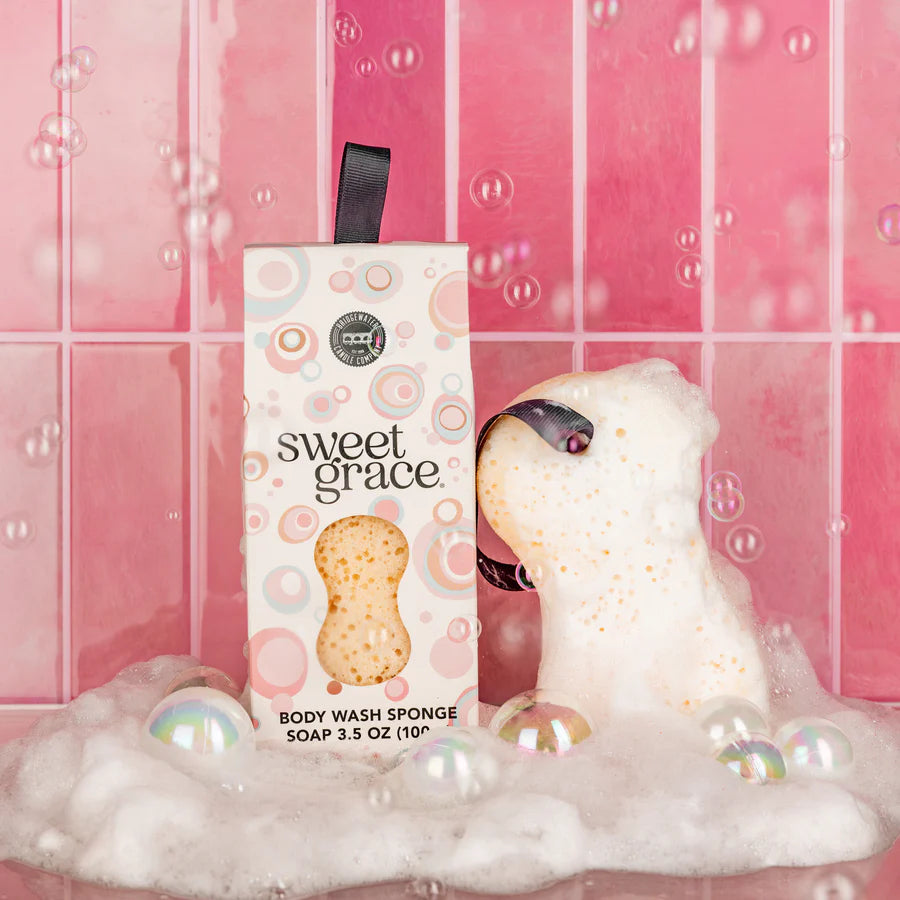 Sweet Grace Body Wash Soap Sponge set next to its box packaging in front of a pink tiles