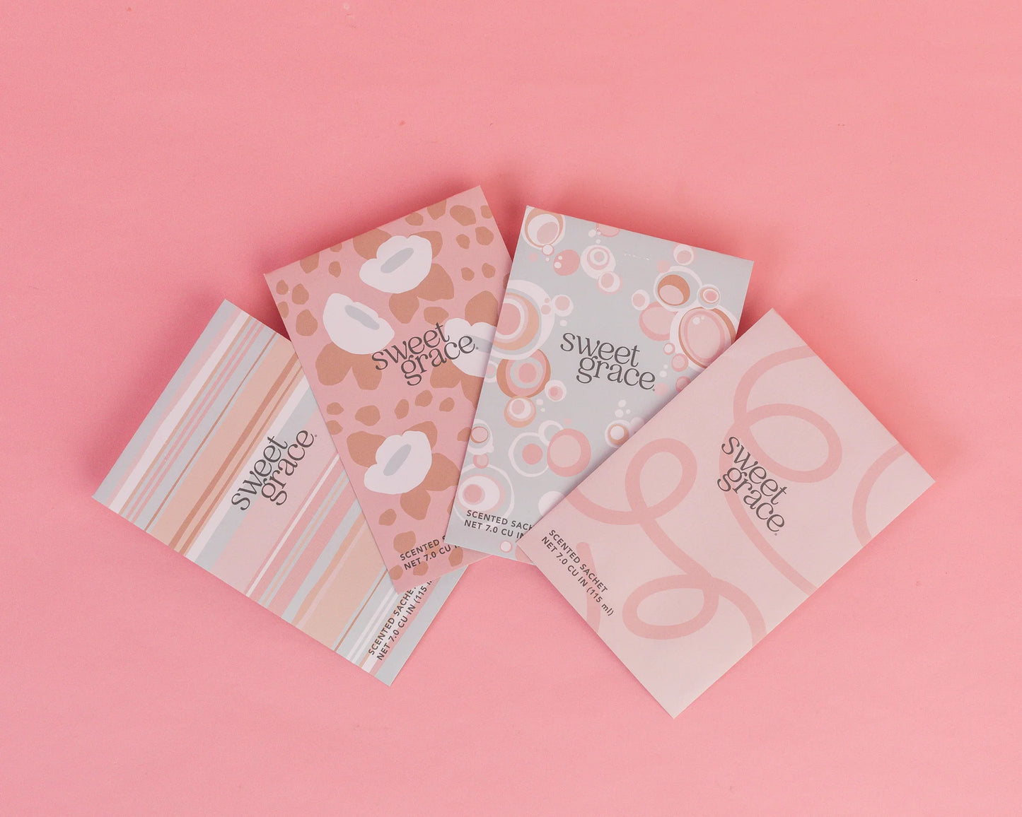 assorted Sweet Grace Scented Sachets fanned out across a pink background