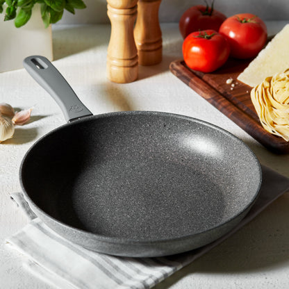 fry pan set on a dish towel on a countertop with veggies and seasoning around it.