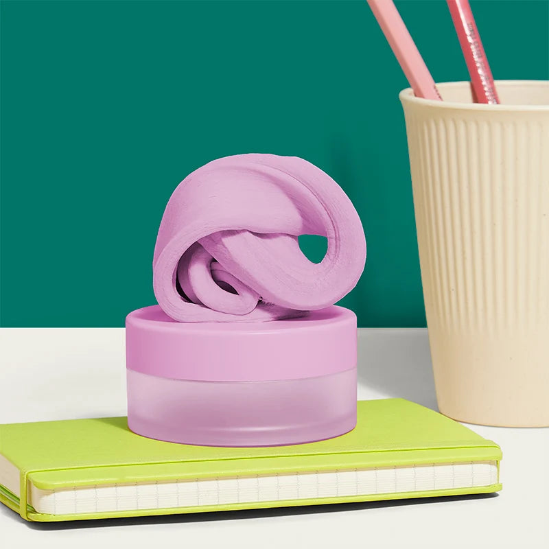 Pink fidget putty set on a green notebook with a beige cup and pink straws in the background.