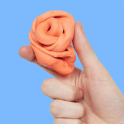 Hand holding a ball of orange fidget putty against a blue background