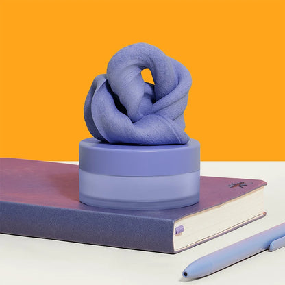 Blue knotted fidget putty on a purple container with a pen and notebook against an orange background