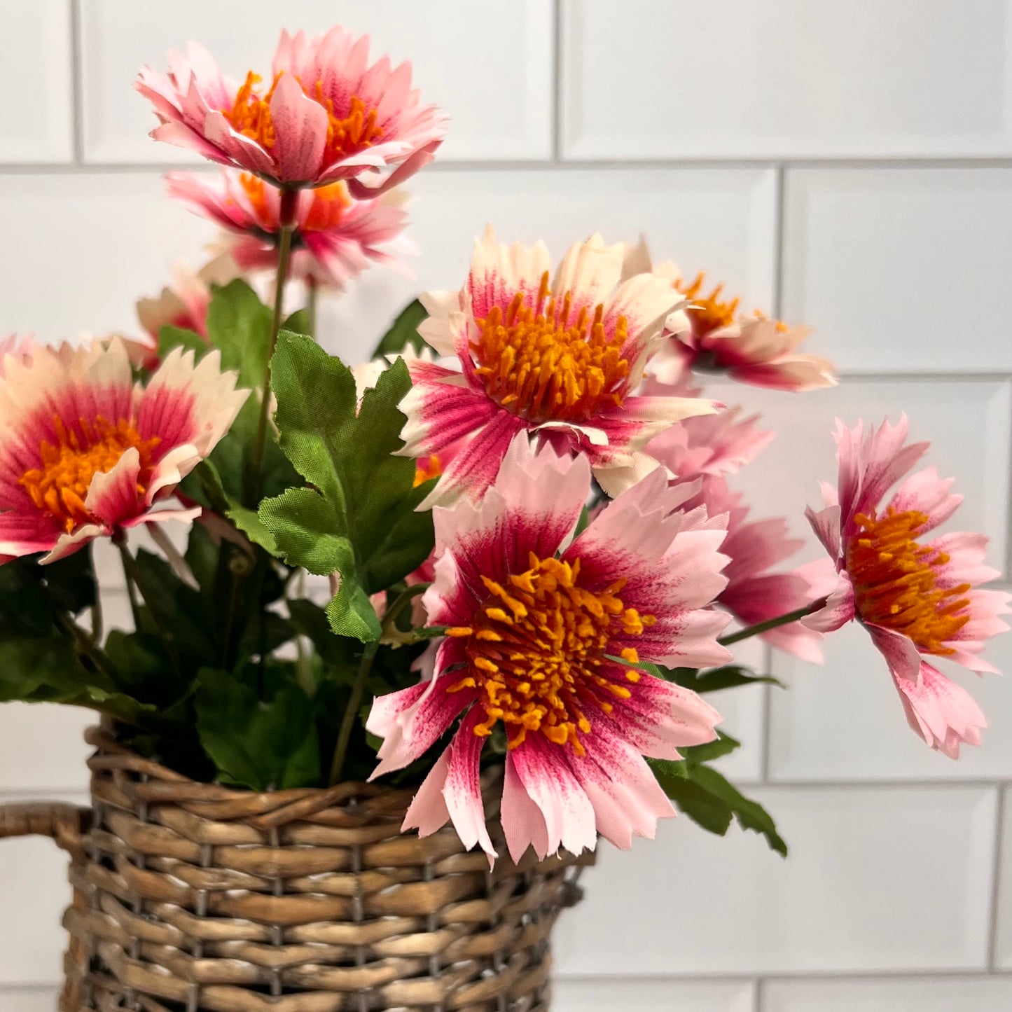 flower bunch in a woven vase with a subway tile background.