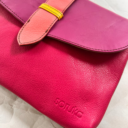 close-up of bright pink saddle bag with pink flap and peach tab.