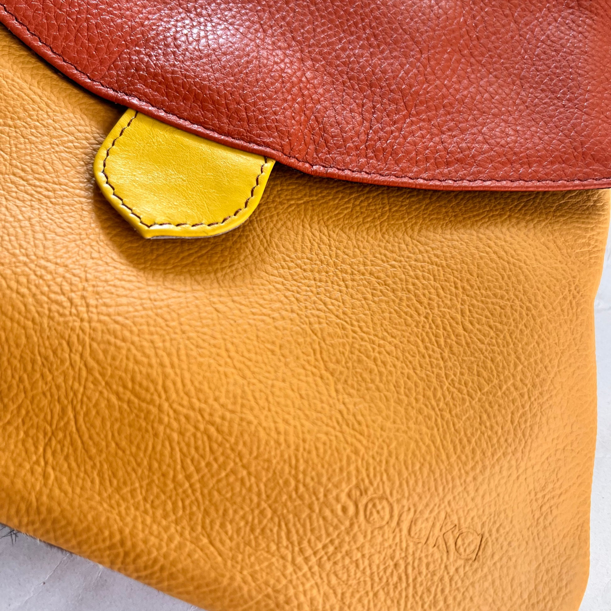 close-up of yellow greta bag with orange flap.