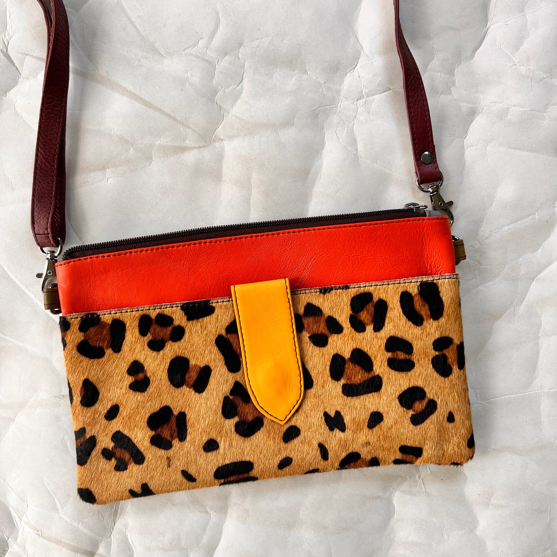 orange rectangular bag with cheetah print pocket, brown shoulder strap.