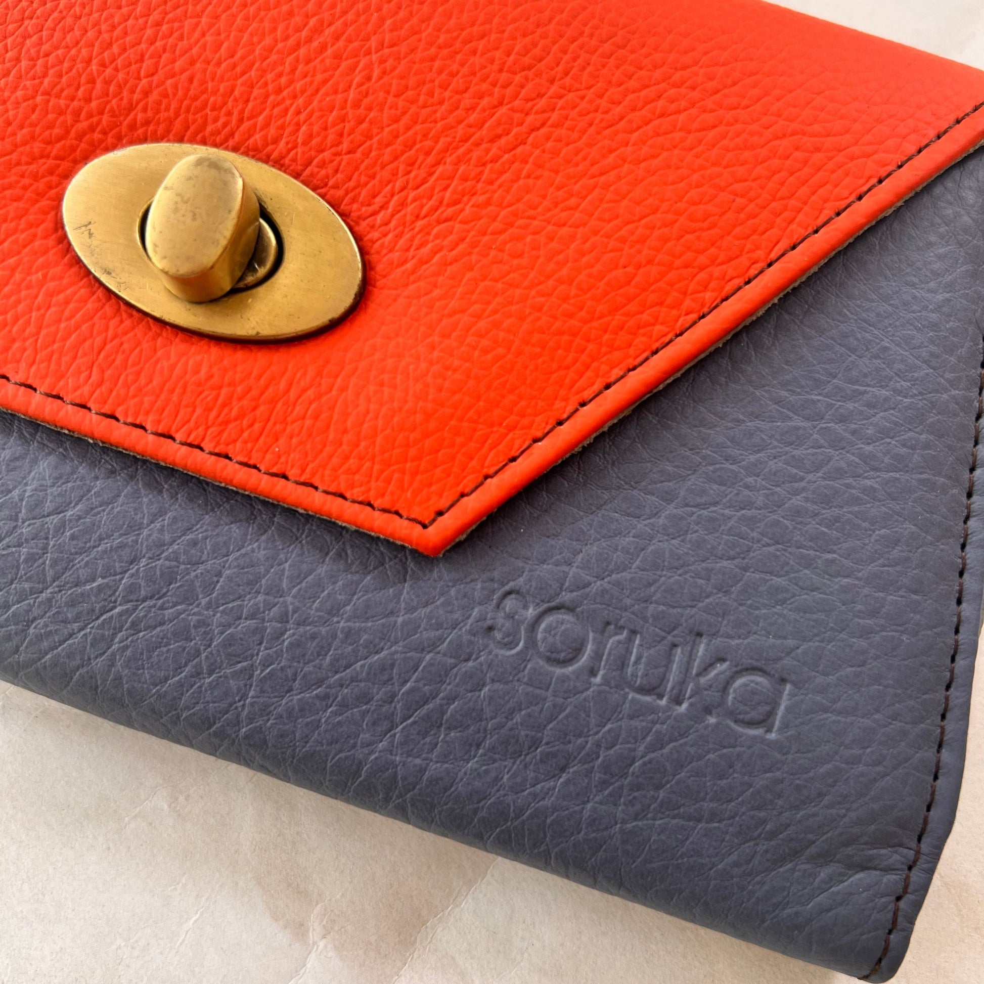 close-up of blue secret clutch wallet with orange flap.