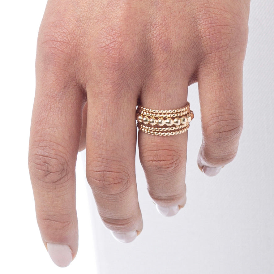 hand with stacked beaded gold rings
