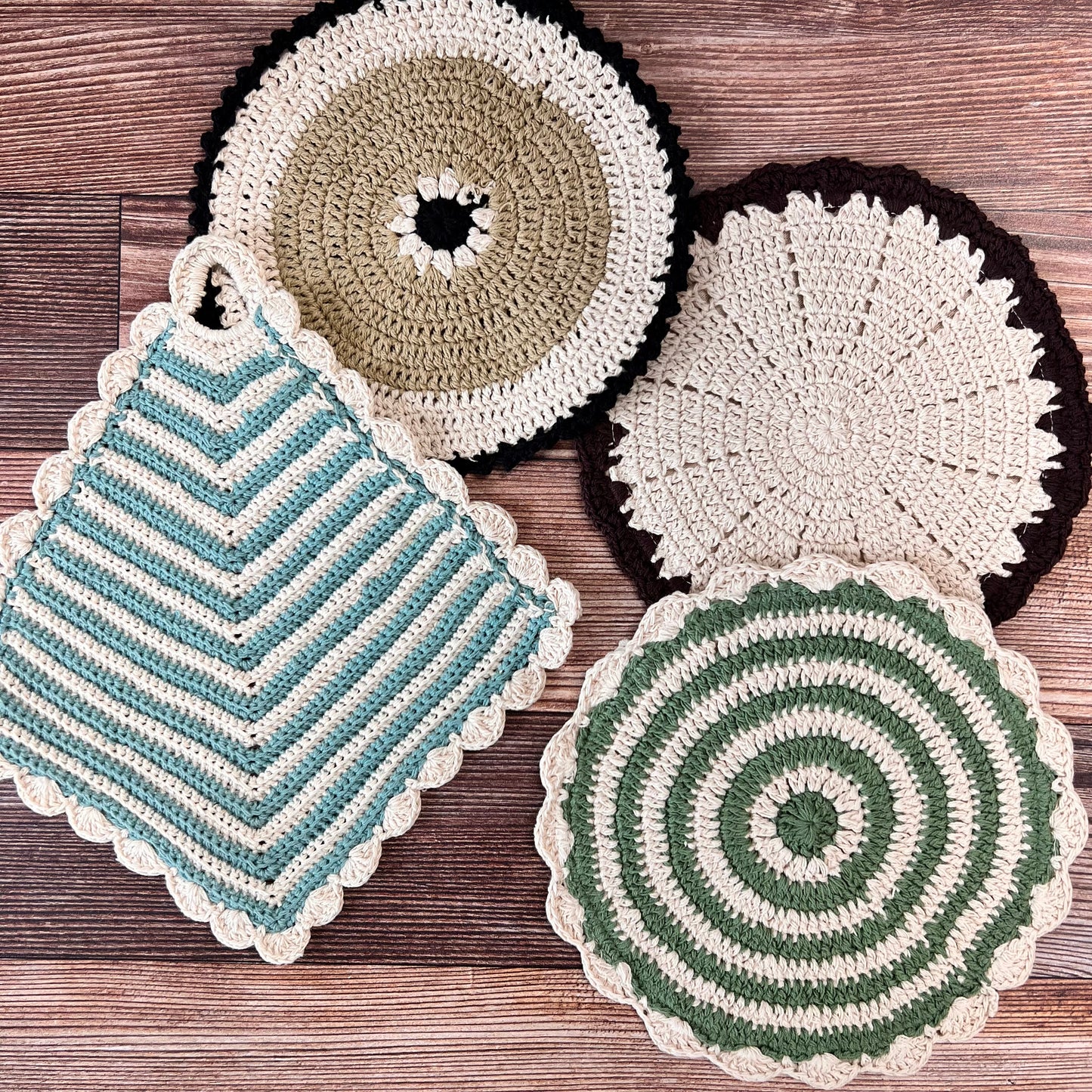 4 styles of crocheted pot holders arranged on a wooden surface.