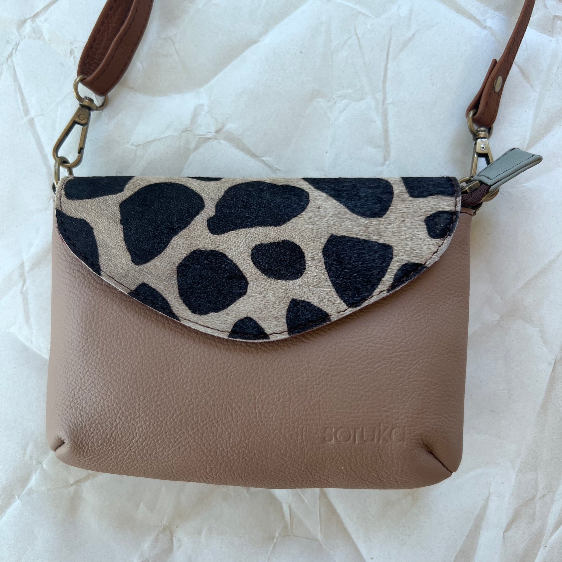 small taupe carol bag with black and white animal print flap and brown shoulder strap.