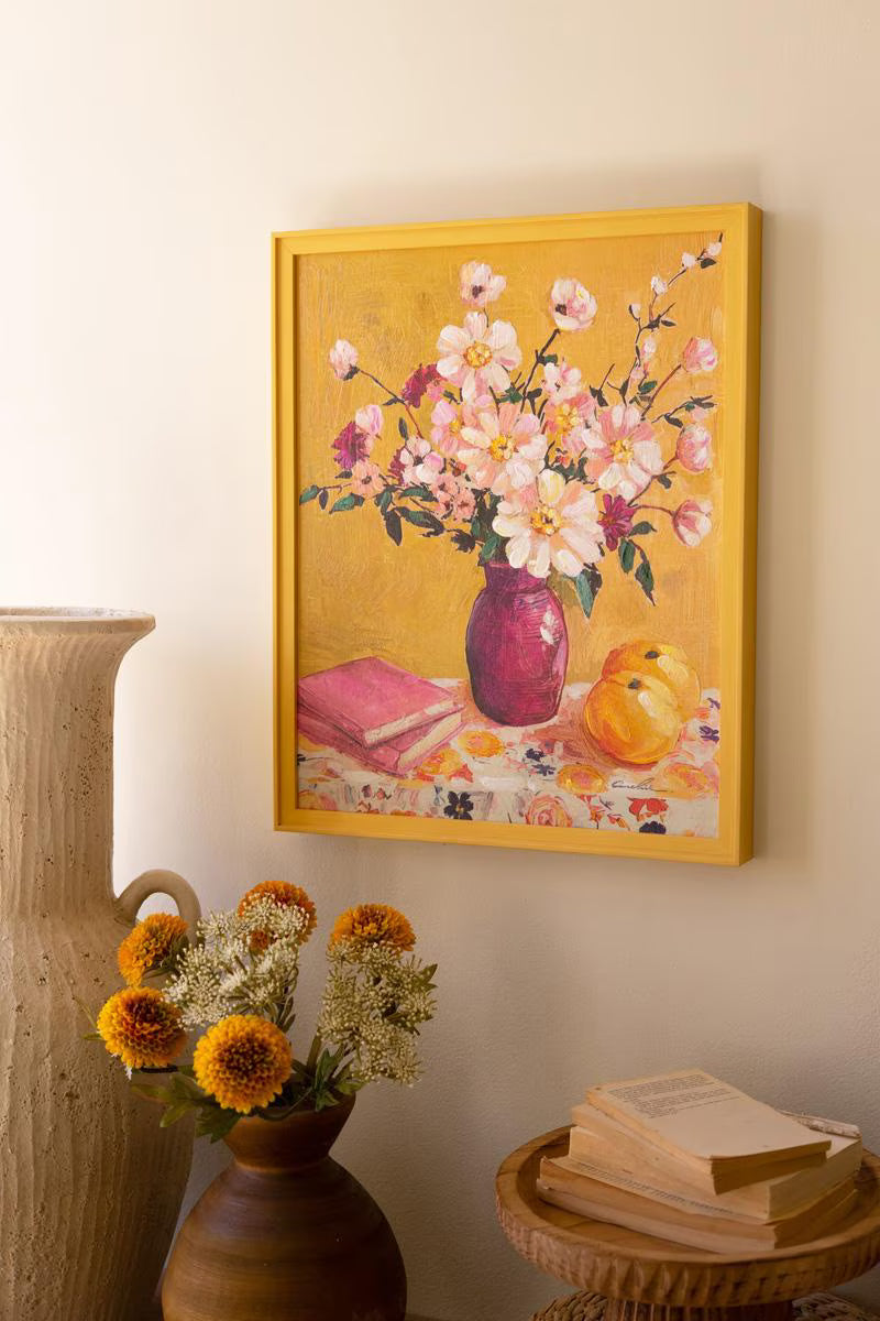 Framed painting of a floral still life on a wall with a with decorative items on the table below