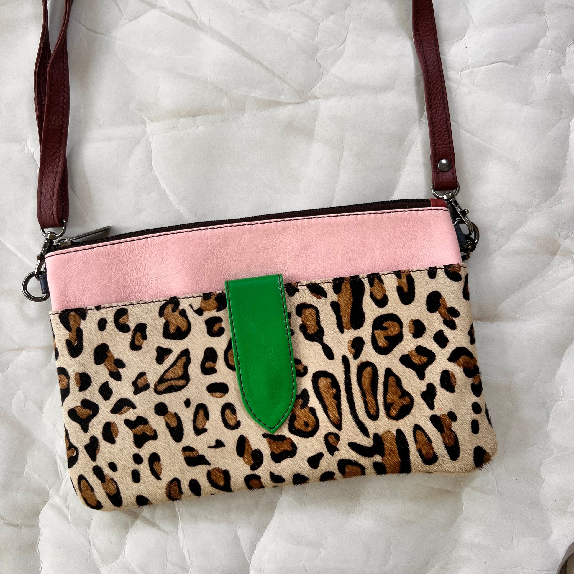 green rectangular bag with cheetah print pocket, green tab, and brown shoulder strap.