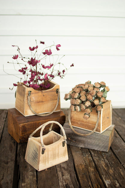 wooden handbag shaped boxes arranged on a wooden table, 2 of the planters have florals in them.