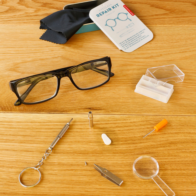eyeglass repair kit displayed open  on a wooden table next to glasses