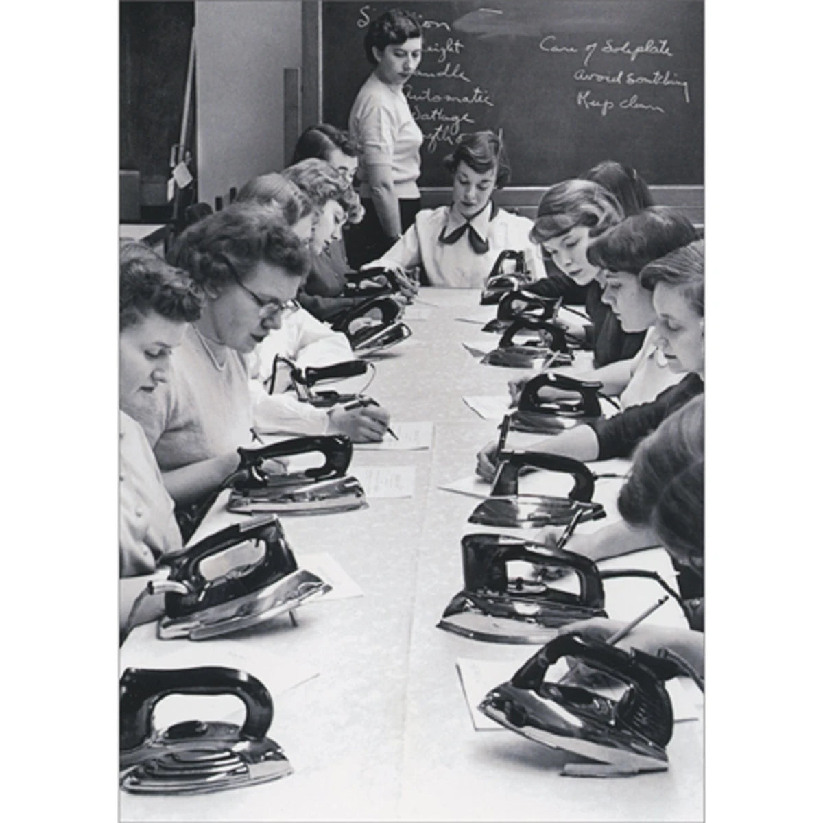 front of card is a black and white photo of women lined up along a table learning how to iron