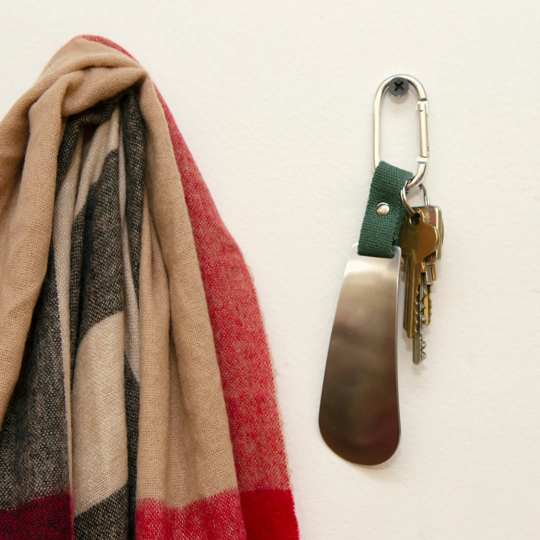 Clippable Shoehorn with keys attached to the carabiner and hung on a nail in the wall.
