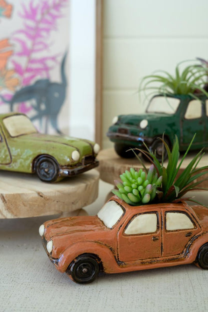 Close up of ceramic car planters with succulents in them.