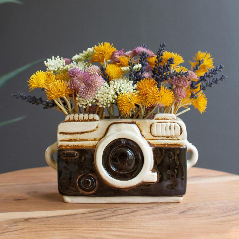 Black and white ceramic Camera planter filled with colorful flowers.
