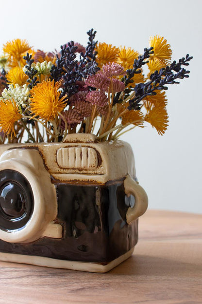Close up of camera planter filled with colorful flowers.