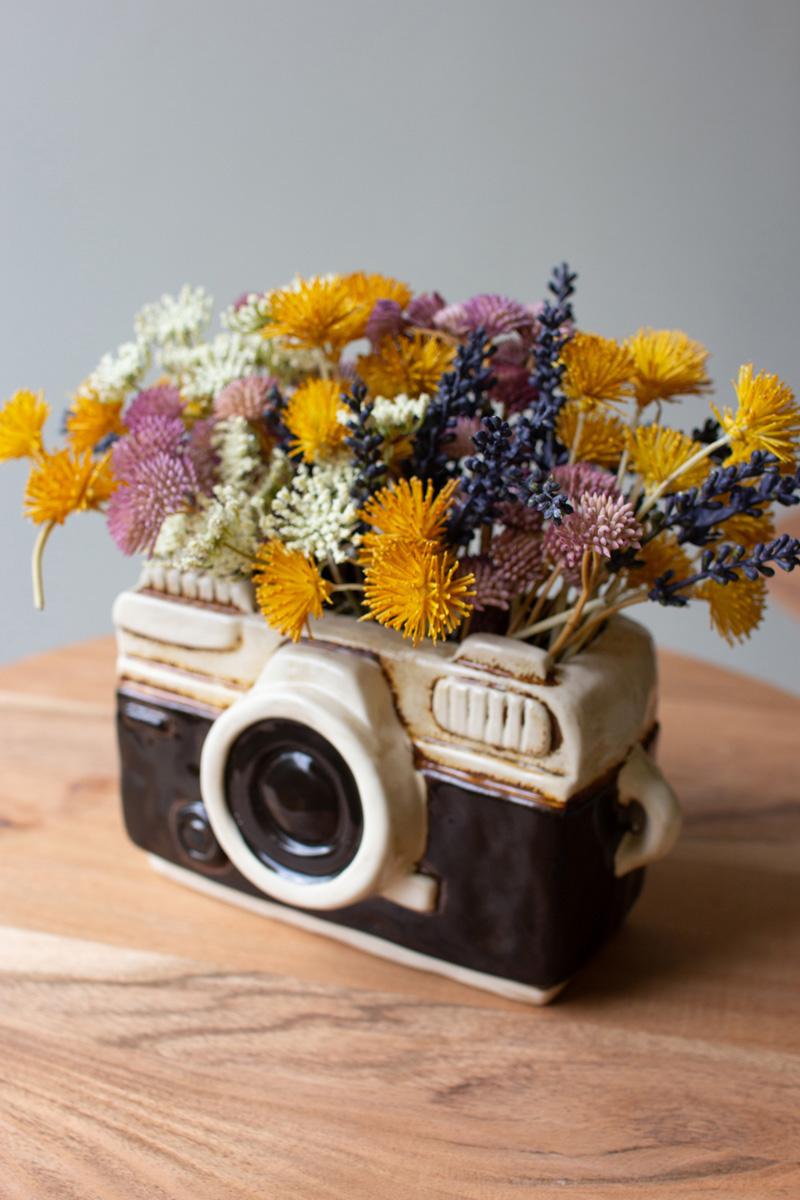 Angled top view of black and white camera planter filled with colorful flowers.