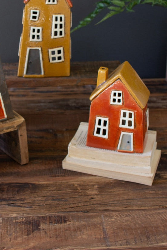 Red wonky house with yellow roof set on a stack of books.