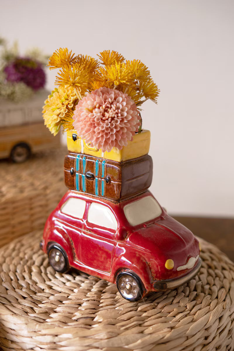 red Ceramic Car With Luggage Planter filled with orange and pink flowers set on a basket