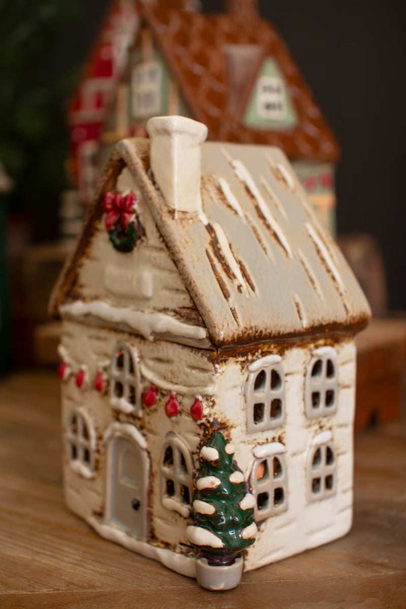 side view of Decorative ceramic house with Christmas decorations on a wooden surface