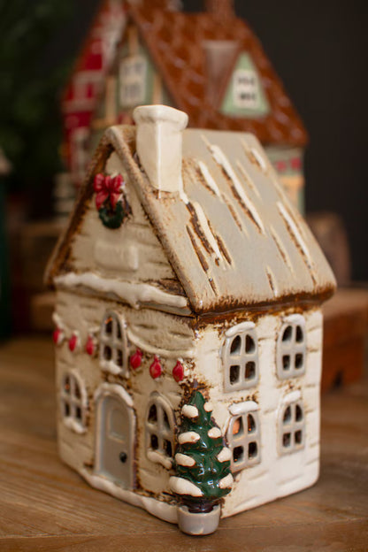 side view of Decorative ceramic house with Christmas decorations on a wooden surface