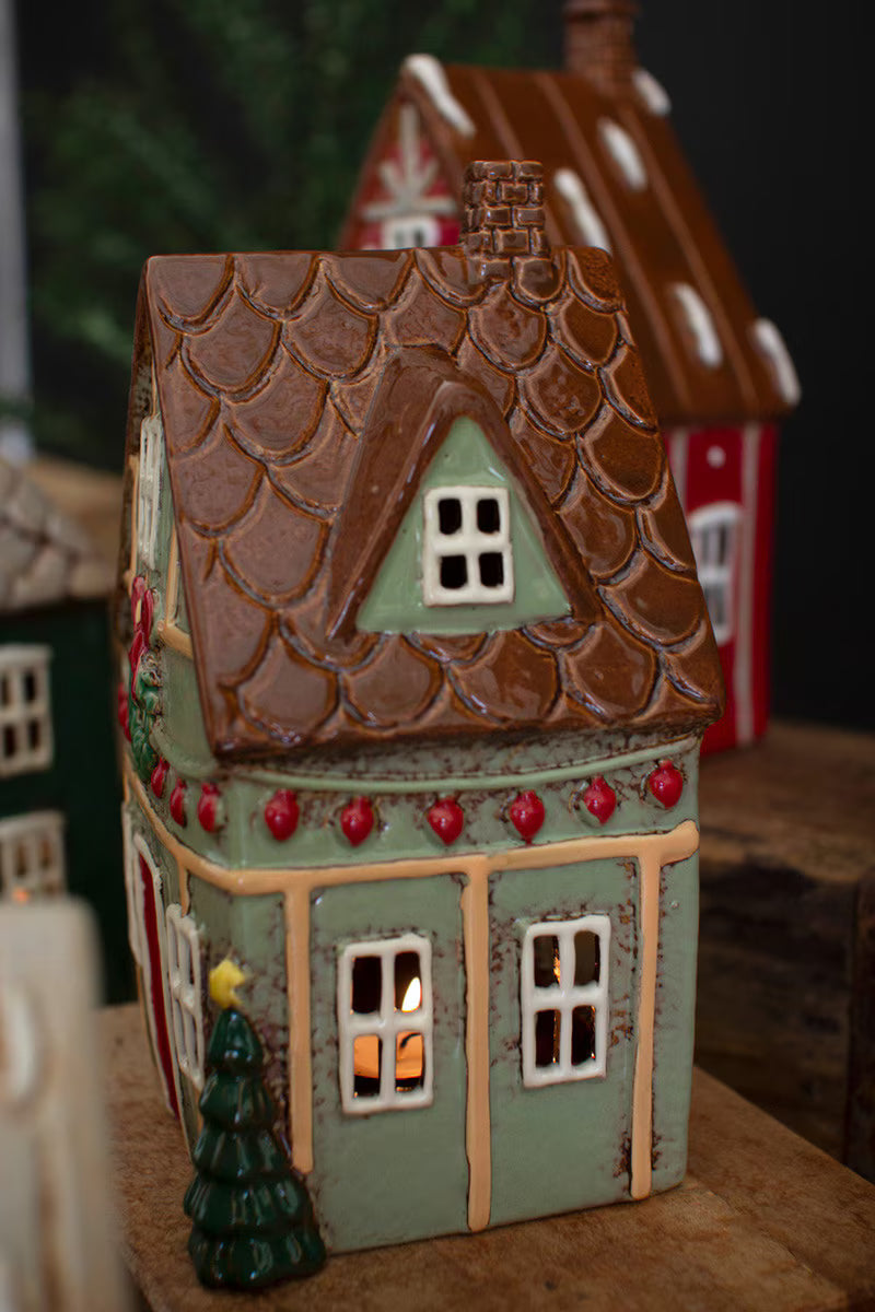 side view of Decorative light green house with a lit interior on a wooden surface.