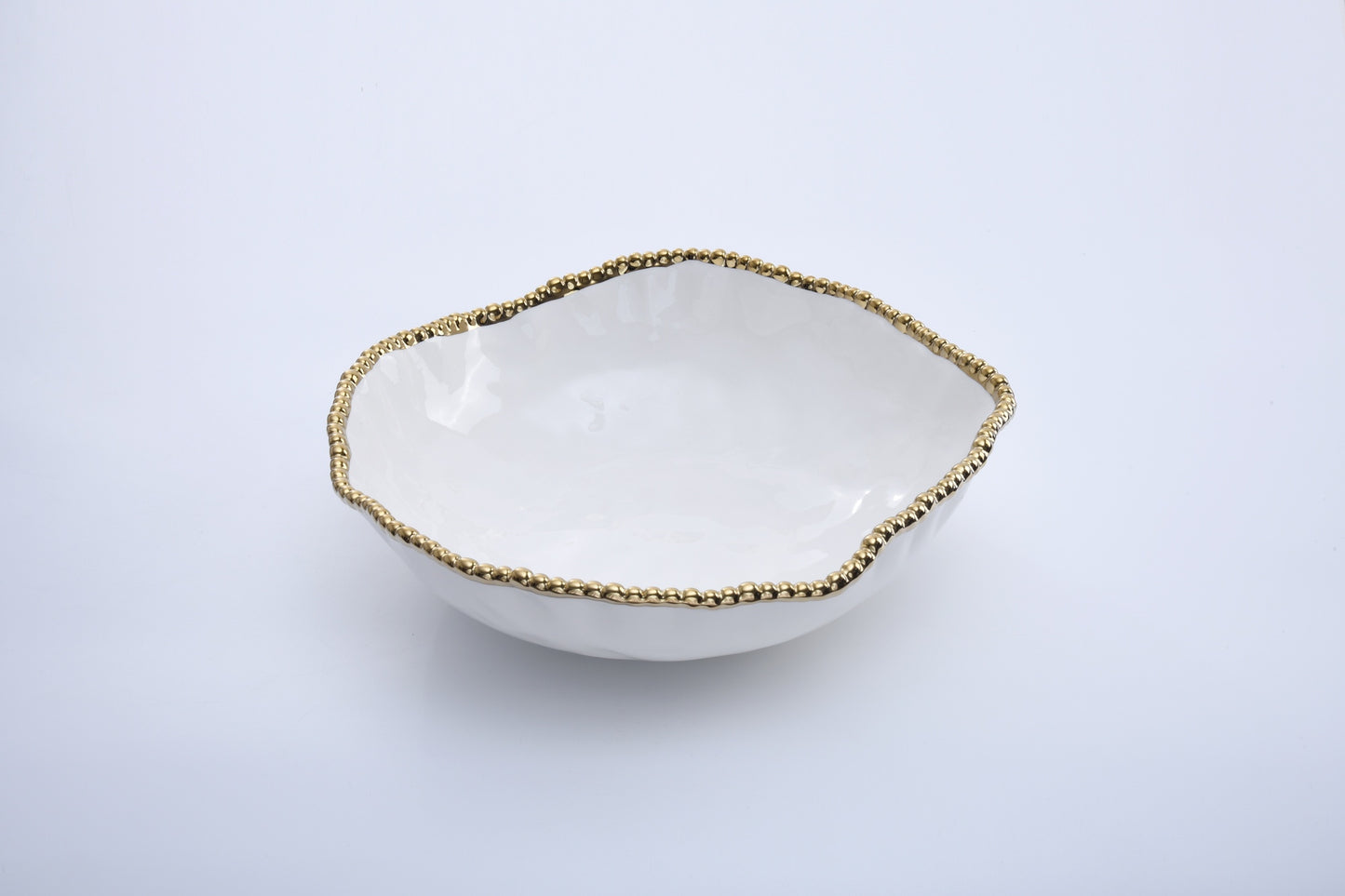 White ceramic bowl with gold beaded rim on a light gray background