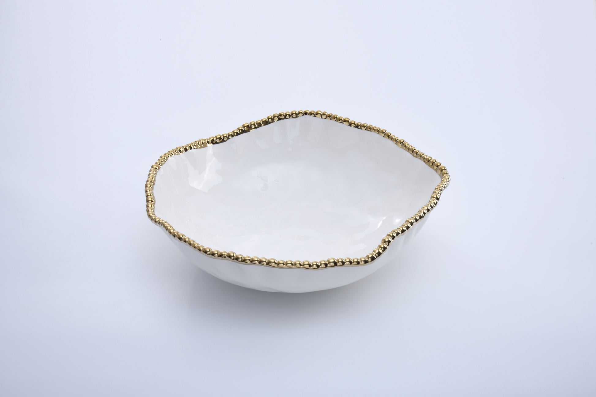 White ceramic bowl with gold beaded rim on a light gray background
