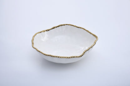 White ceramic bowl with gold beaded rim on a light gray background