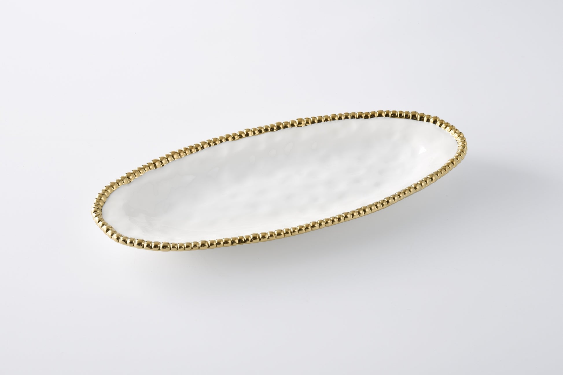 white oval serving platter with gold beaded rim shown on a white background
