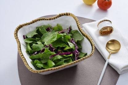 top view of white square bowl with gold beaded rim filled with green salad