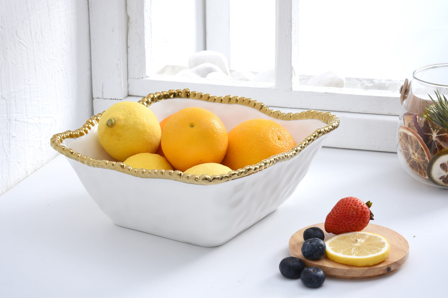 white Square Salad bowl with citrus fruit in it set on a counter in front of a window
