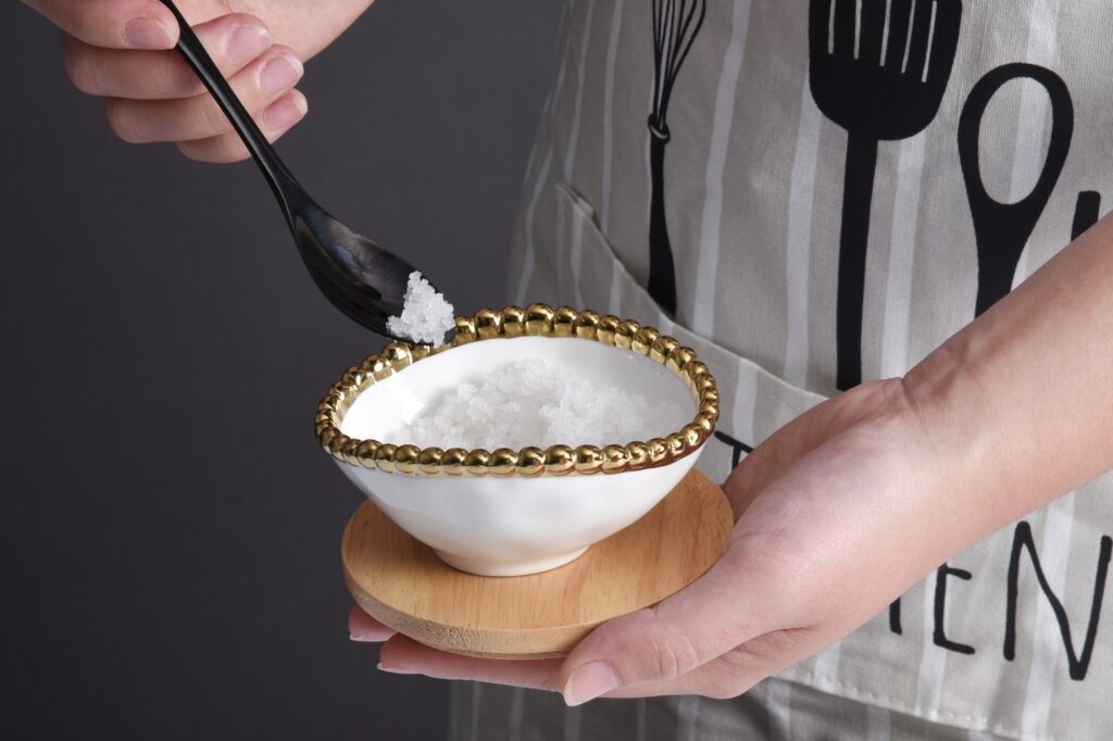 hands holding small white and gold bowl filled with salt