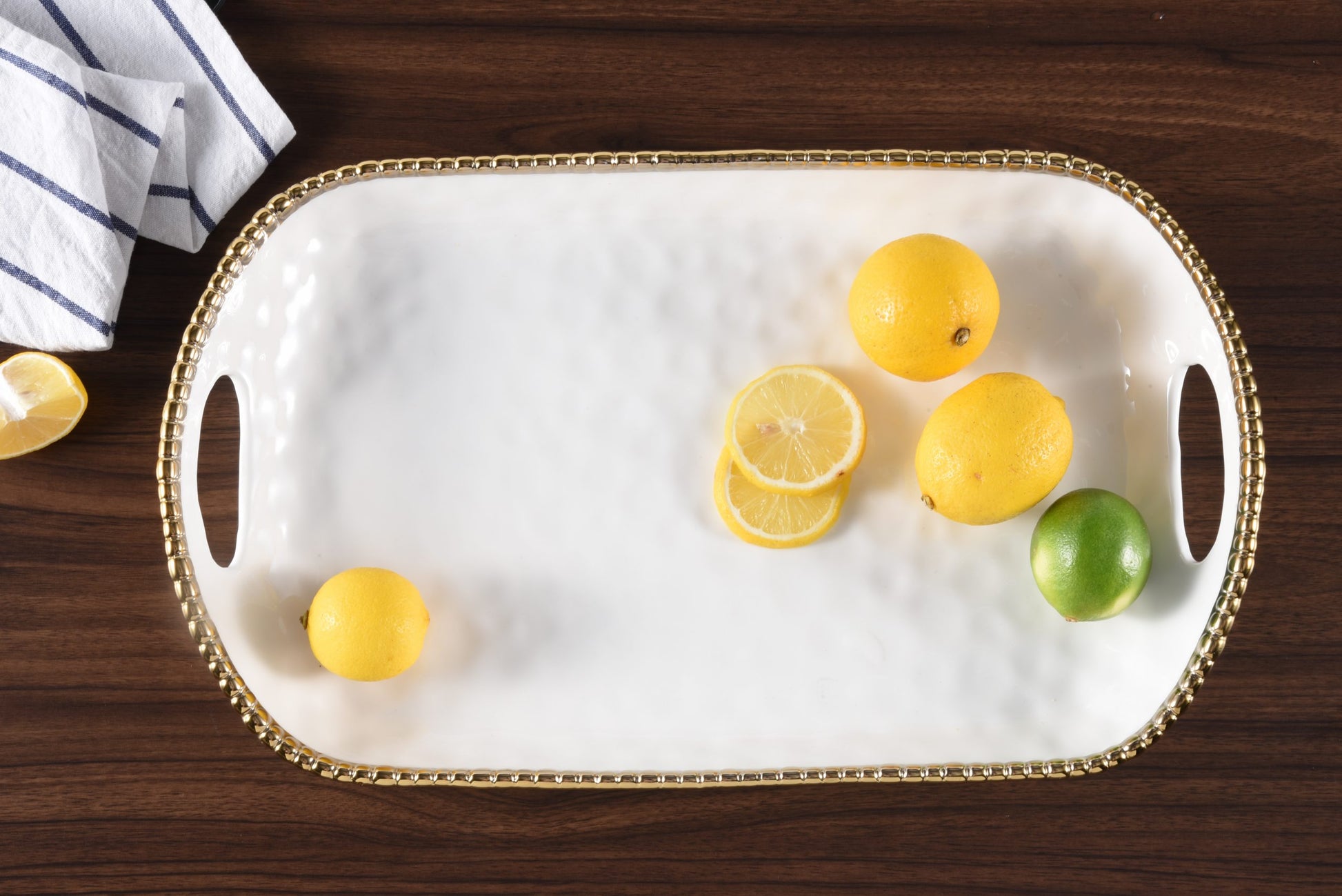 white Rectangular Tray with gold rim and Handles with citrus fruit on it

