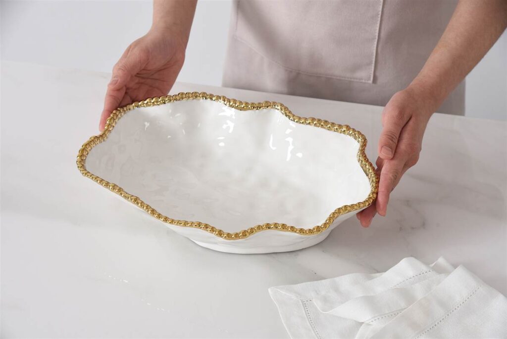 hands holding white bowl with golden beading on rim