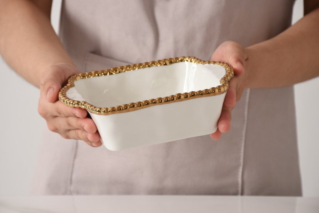 hands holding white and gold ceramic mini baker