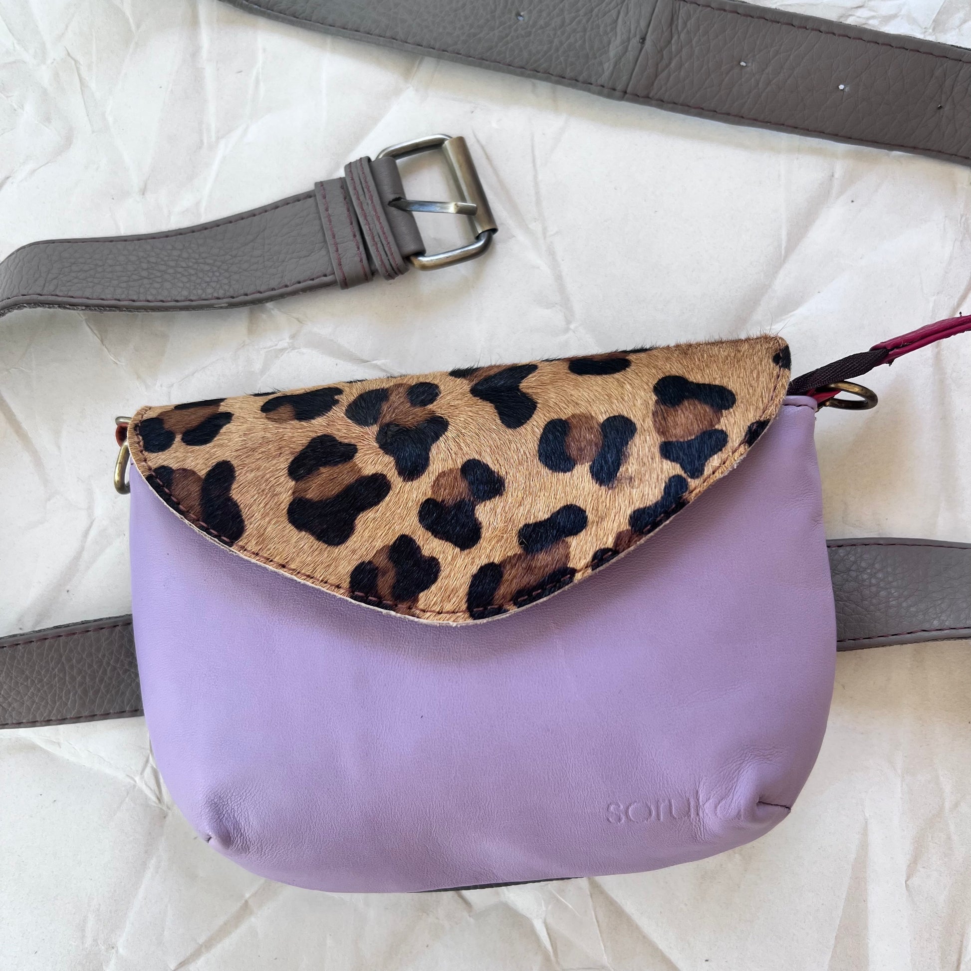 small lavender carol bag with cheetah print flap and grey belt.