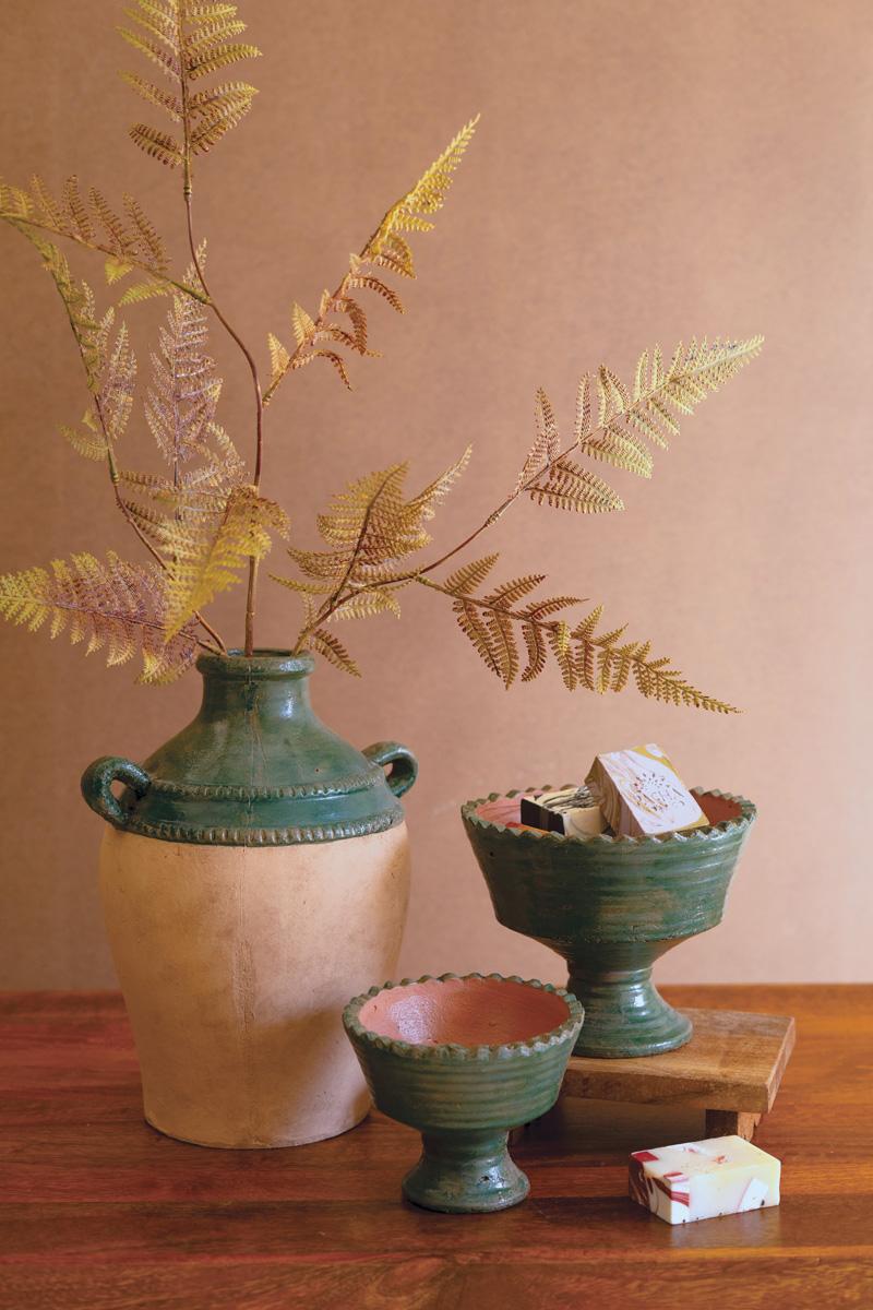 Decorative setting with ceramic vases and fern fronds on a wooden surface.