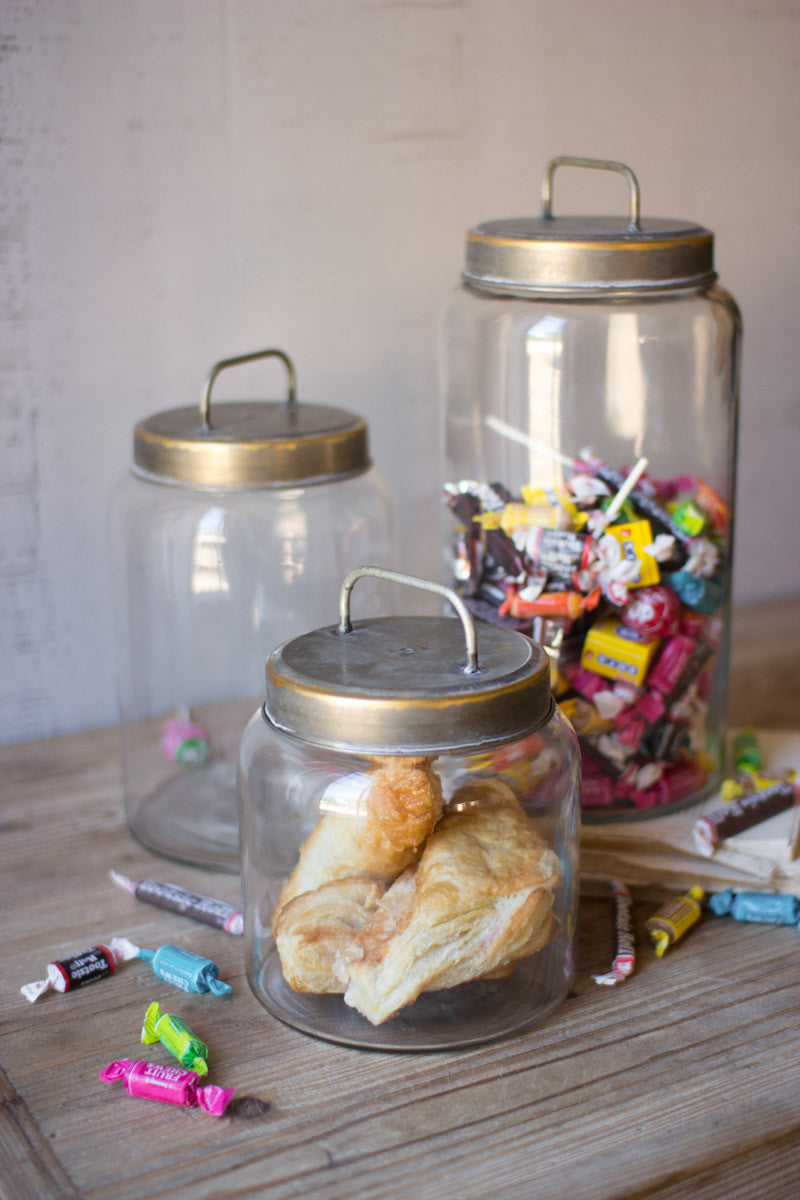 3 sizes of glass canisters, large is filled with candy, medium is empty, small has coisants in it.
