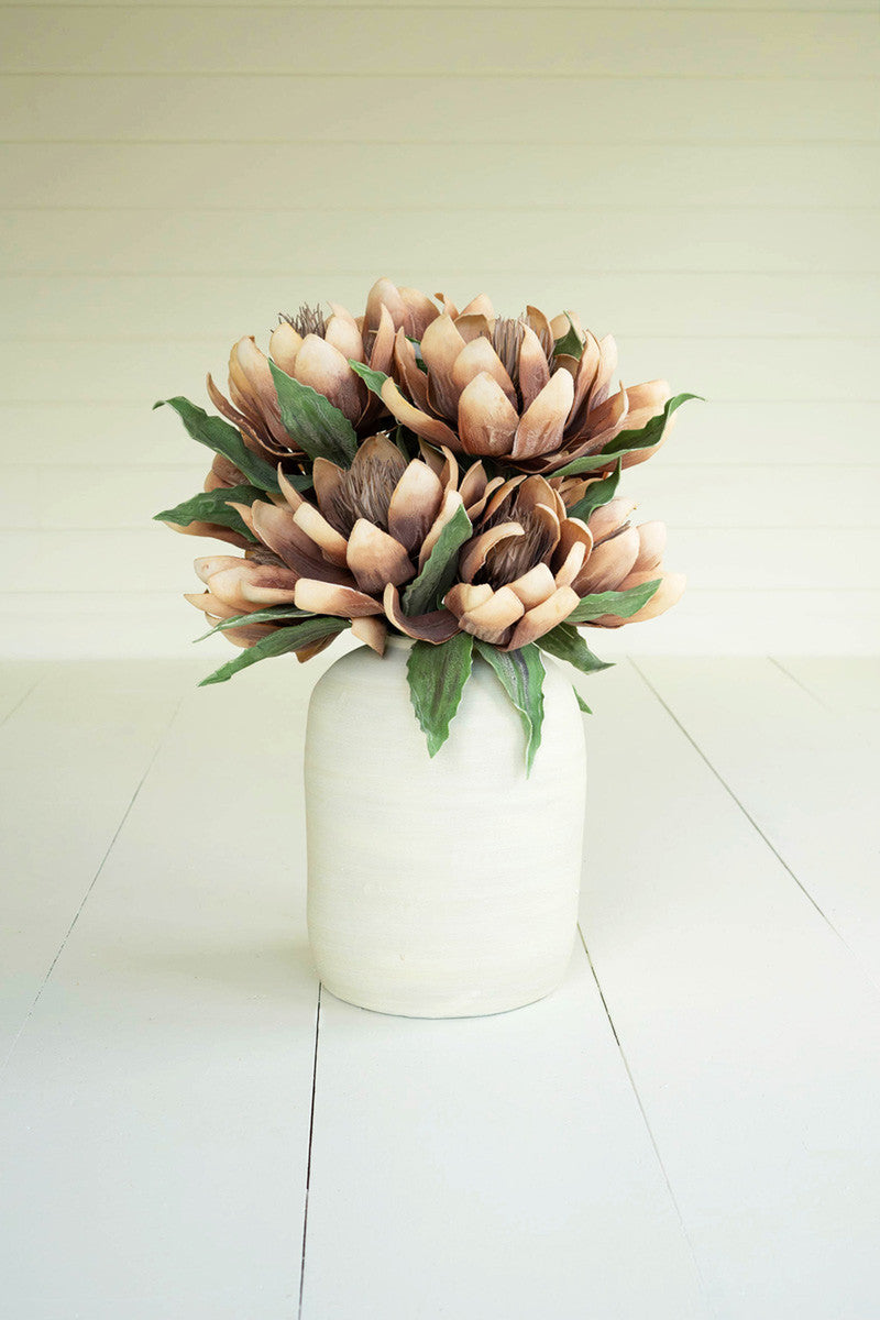 arrangement of floral blosssom stems in a white vase on a white slat table.