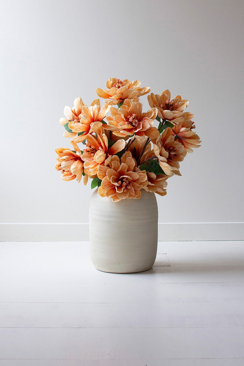 White vase filled with orange flowers on a white background