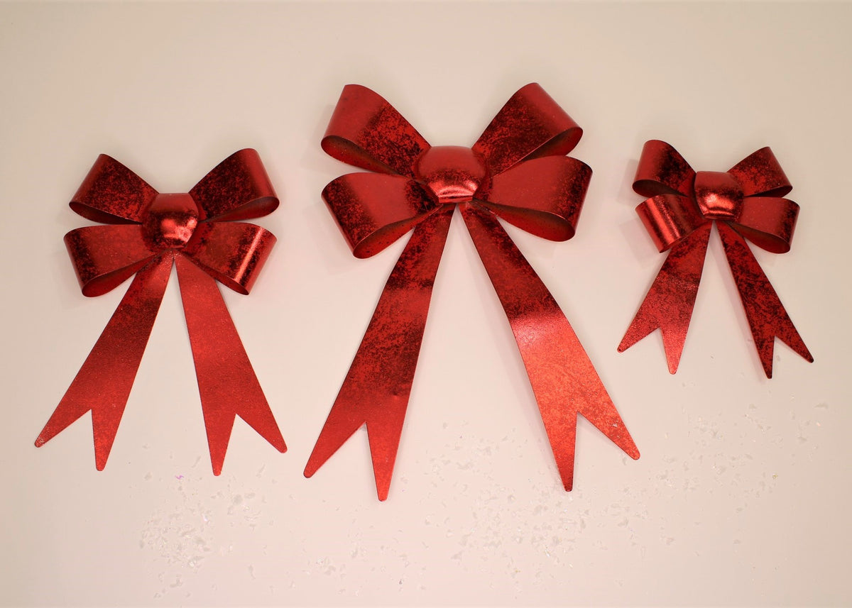 three red metal bows of different sizes on a tan background