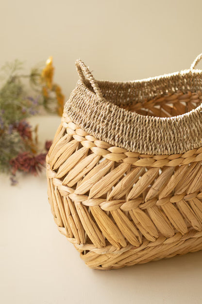 close-up of a Seagrass Basket with Two Handles shown on a beige background