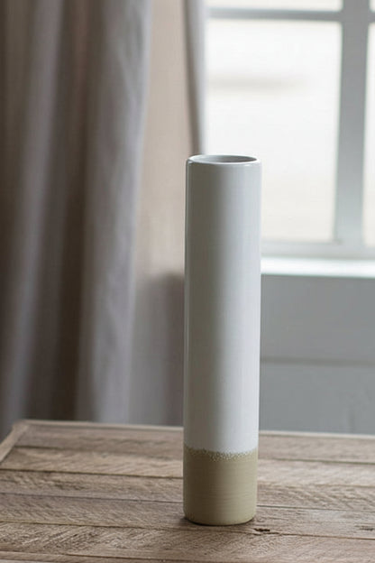 tall Ceramic Cylinder Bud Vase set on a wooden table with window and curtains in the background