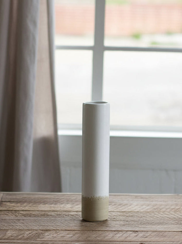 medium Ceramic Cylinder Bud Vase set on a wooden table with window in the background