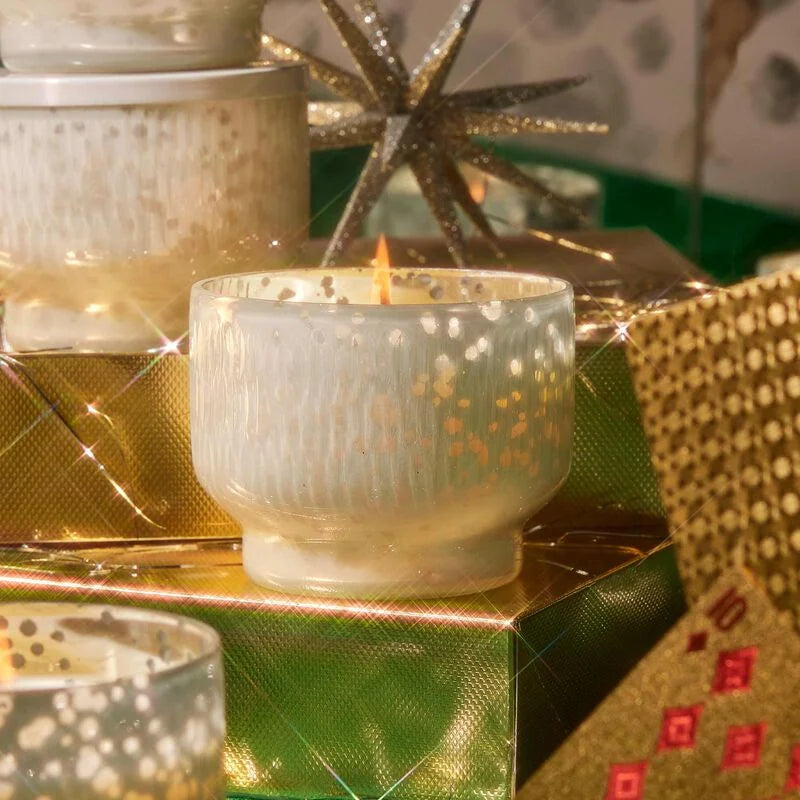 lit Crystal Pine Inverted Jar Candle arranged on a table with gifts wrapped in gold paper.